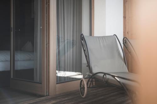 a chair sitting in front of a glass door at Hotel Alpenblick in Sesto