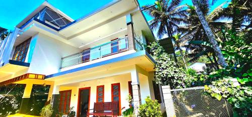 a white house with a palm tree in front of it at Dean Dale Cottages in Thekkady