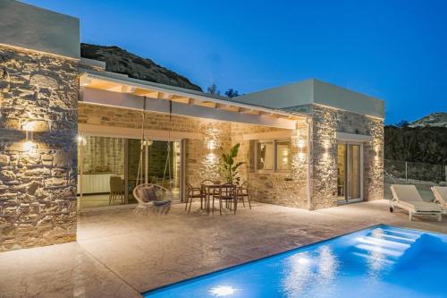 a villa with a swimming pool at night at Villa Vidan in Matala by South Cretan Villas in Matala
