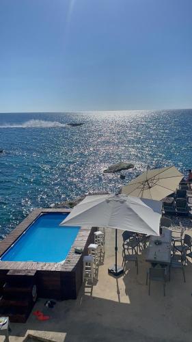 a swimming pool with chairs and umbrellas next to the ocean at Golden Stone Beach in Halat Byblos