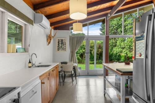 a kitchen with white counters and a large window at Pearl Magic - Mangawhai Heads Holiday Home in Mangawhai