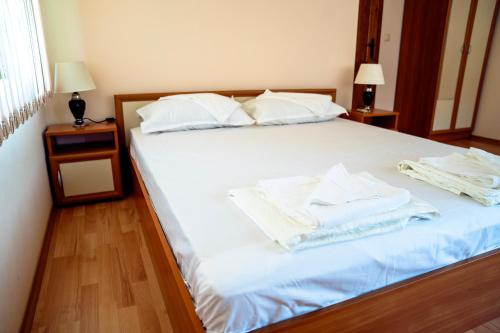 a bed with white sheets and towels on it at Къща за гости Далинда in Byala