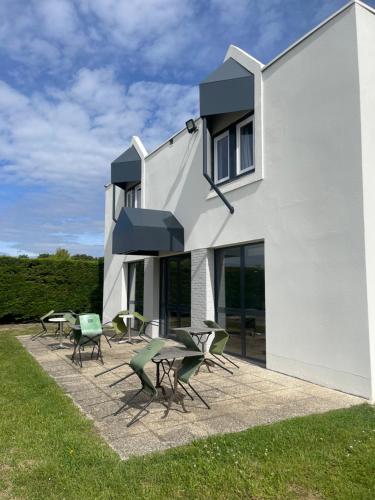 a white building with chairs and tables in front of it at Kyriad Direct Dreux in Dreux