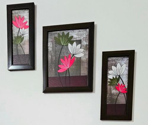 three framed pictures of flowers on a wall at Dean Dale Cottages in Thekkady