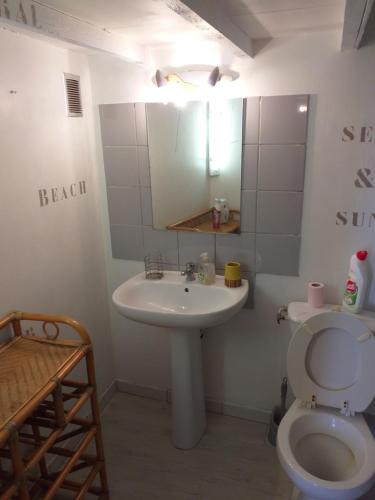 une salle de bain avec un lavabo, des toilettes et un miroir dans l'établissement le drop point des rencontres photos, à Arles
