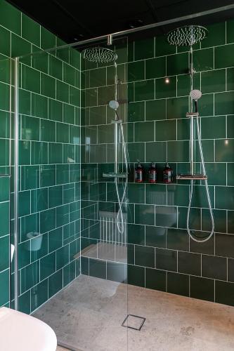 a bathroom with green tiled walls and a shower at Stufvenäs Gästgifveri in Söderåkra
