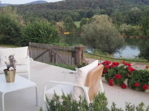 eine Terrasse mit weißen Stühlen und Blick auf einen See in der Unterkunft Holiday Home Evelin with Krka view in Cerklje ob Krki
