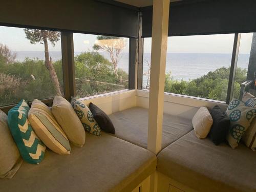 a row of pillows sitting in a room with windows at Points South By The Sea in Apollo Bay