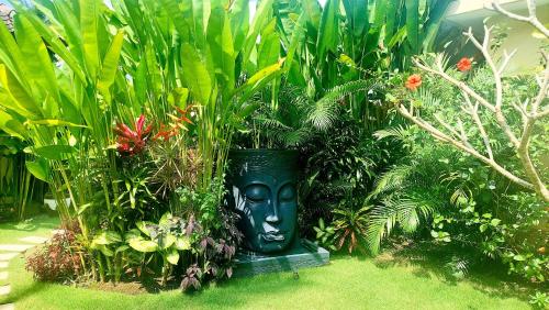 a green statue in a garden with plants at TAMAN EDEN COTTAGE in Ubud