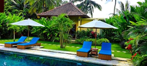 a group of chairs and umbrellas next to a pool at TAMAN EDEN COTTAGE in Ubud