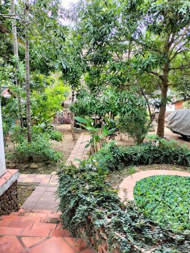 a garden with a brick path and trees and a bench at Jungle House Kep in Kep
