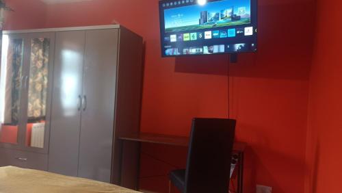 a bedroom with a tv on a red wall at L'Auberge close Syon Lane Station and Heathrow in London