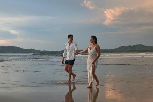a man and a woman walking on the beach at Jardin del Eden Boutique Hotel in Tamarindo