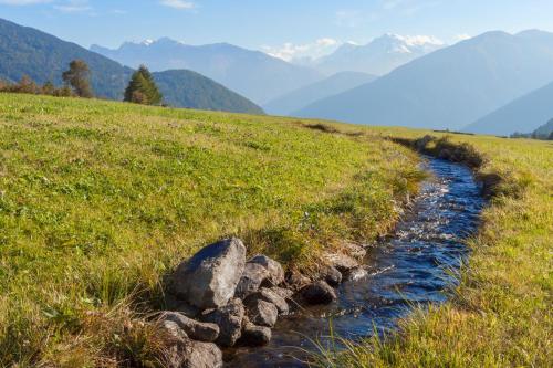 a stream in a field with mountains in the background at Garni Marianne in Malles Venosta