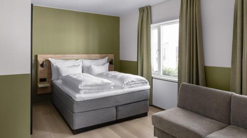 a small bedroom with a bed and a chair at Comfort Hotel Trondheim in Trondheim