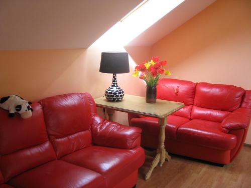 a living room with a red couch and a table with flowers at Skaistie Majori in Jūrmala