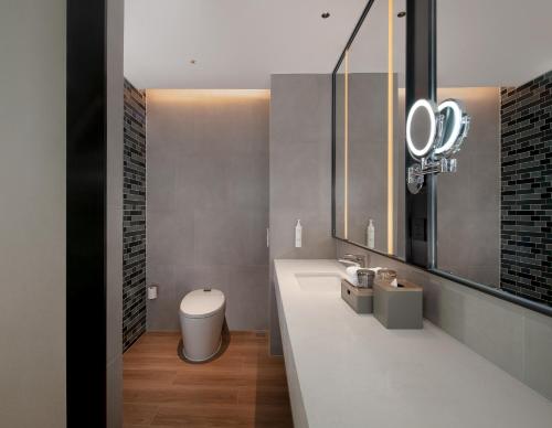 a bathroom with a sink and a toilet and a mirror at Fairfield by Marriott Shenzhen Bao'an in Shenzhen