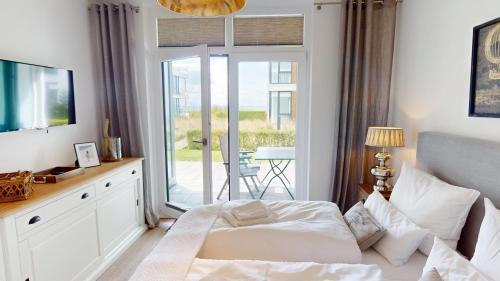 a bedroom with a bed and a sliding glass door at Südkap B-03 in Pelzerhaken