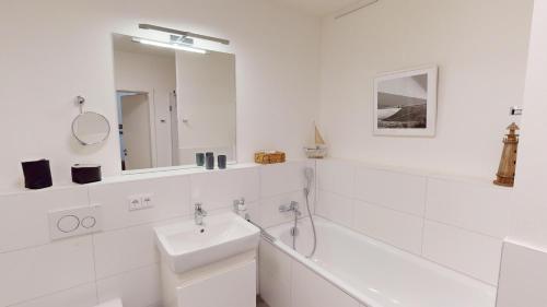a white bathroom with a sink and a mirror at Südkap B-03 in Pelzerhaken