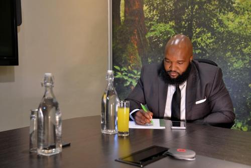a man in a suit sitting at a table at Cresta Lodge Harare in Harare