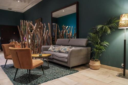 a living room with a couch and some plants at Comfort Aparthotel Saint-Etienne in Saint-Étienne