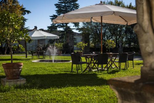 a table and chairs under an umbrella in a yard at Hotel Villa Cornér Della Regina in Vedelago