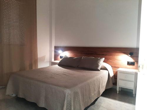 a bedroom with a bed with a wooden headboard at APCOSTAS - Complejo Al Andalus in Alcossebre