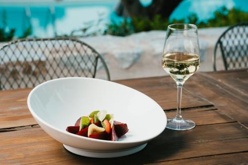 a bowl of fruit and a glass of wine on a table at 100 Rizes Seaside Resort- Small Luxury Hotels of the World in Gythio
