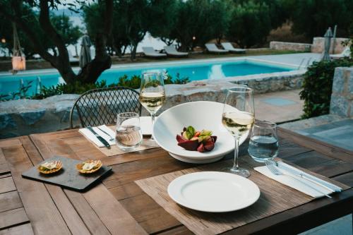 a table with a bowl of fruit and glasses of wine at 100 Rizes Seaside Resort- Small Luxury Hotels of the World in Gythio