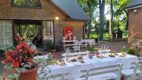 a table with white tables and chairs in a yard at Jumpravas pils in Jumprava