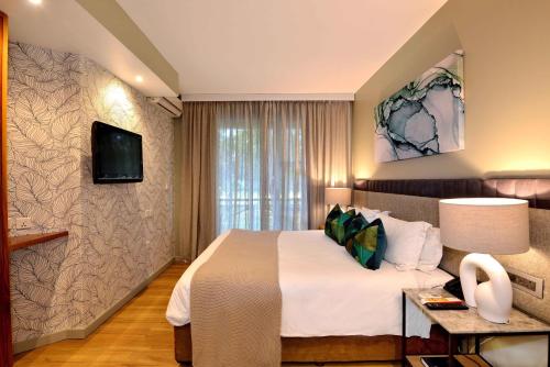 a hotel room with a bed and a tv at Cresta Lodge Harare in Harare