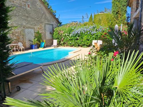 une piscine dans un jardin avec des fleurs et des plantes dans l'établissement Le gîte de Sainte Valière PISCINE,SPA et CLIMATISATION, à Sainte-Vallière