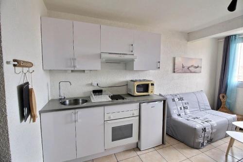 une cuisine avec des armoires blanches, un évier et un micro-ondes dans l'établissement Studio MIMIZAN à 150m plage place du marché mimizan, à Mimizan