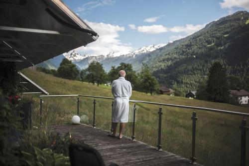 a man standing on a wooden walkway looking at a mountain at Tanafreida Berg-Refugium in Sankt Gallenkirch