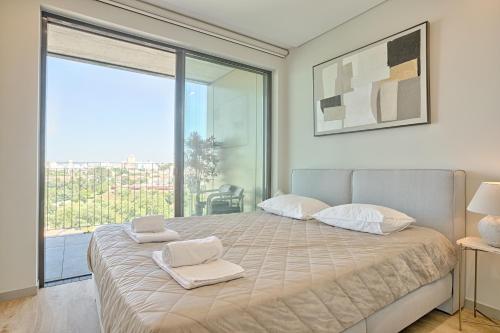 a bedroom with a large bed with two towels on it at Brand New Luxurious Ap T2 - Amazing View- with garage in Vila Nova de Gaia