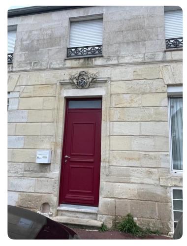 une porte rouge sur le côté d'un bâtiment en pierre dans l'établissement Chambre privée Yoko, à Talence