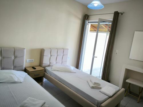 two beds in a room with a window at Aggelika Apartments in Lithakia