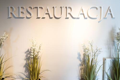 a sign on a wall with plants on it at HOTEL I RESTAURACJA BROCHÓW in Wrocław