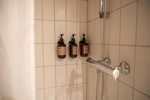 three bottles of soap in a shower in a bathroom at Hotel Siemsens Gaard in Svaneke