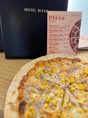 a pizza sitting on a table next to a pizza box at Hotel River in Borşa