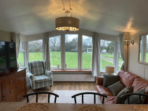 a living room with a couch and chairs and windows at Stunning farm retreat in Tyes Cross