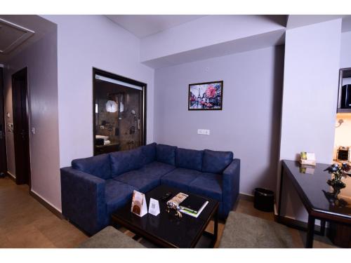 a living room with a blue couch and a table at Belvedere Suites in Greater Noida