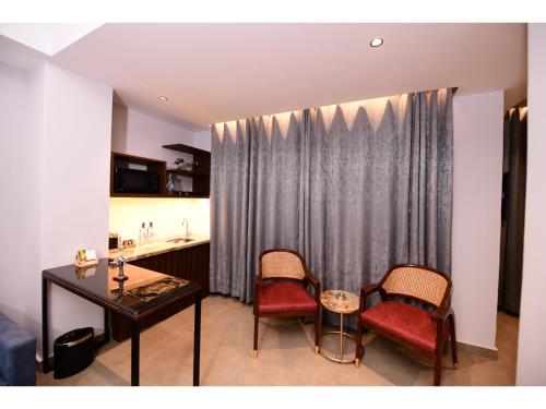 a living room with a table and two chairs and a kitchen at Belvedere Suites in Greater Noida