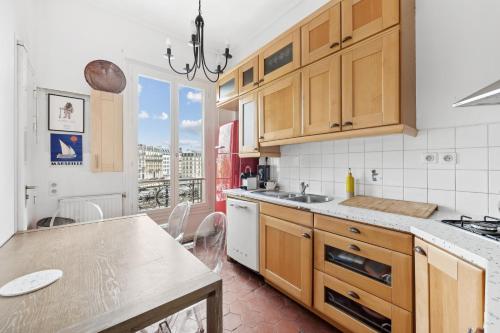 une cuisine avec des placards en bois et une table avec une table dans l'établissement Veeve - Subtly Vintage, à Paris