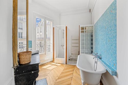 La salle de bains est pourvue d'une baignoire blanche et d'une fenêtre. dans l'établissement Veeve - Subtly Vintage, à Paris