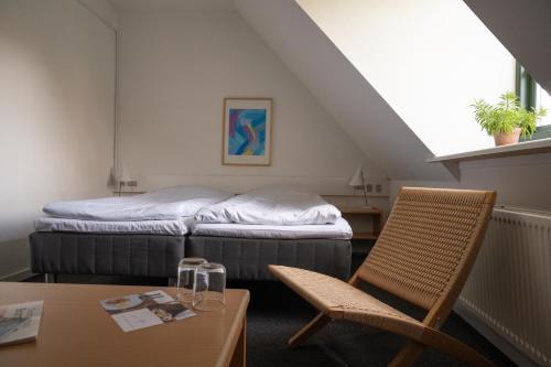 a room with a bed and a table and a chair at Hotel Siemsens Gaard in Svaneke