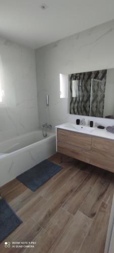 une salle de bain blanche avec une baignoire et un lavabo dans l'établissement Belle maison neuve proche La Rochelle, à Ferrières