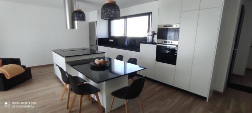 une cuisine avec une table en verre et des chaises noires dans l'établissement Belle maison neuve proche La Rochelle, à Ferrières