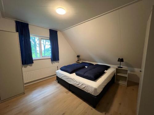 a bedroom with a bed with blue pillows on it at Huisje voor Rust, Ruimte en Natuur in Neede