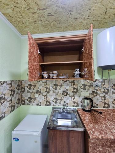 a small kitchen with a sink and a refrigerator at Manan Guesthouse in Chʼkalovka